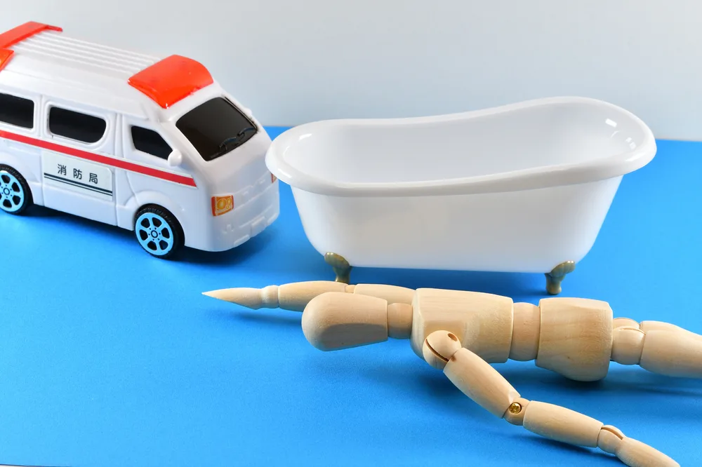 浴槽のそばで倒れた人形と救急車の模型